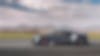 a grey sports car is driving down a road with mountains in the background
