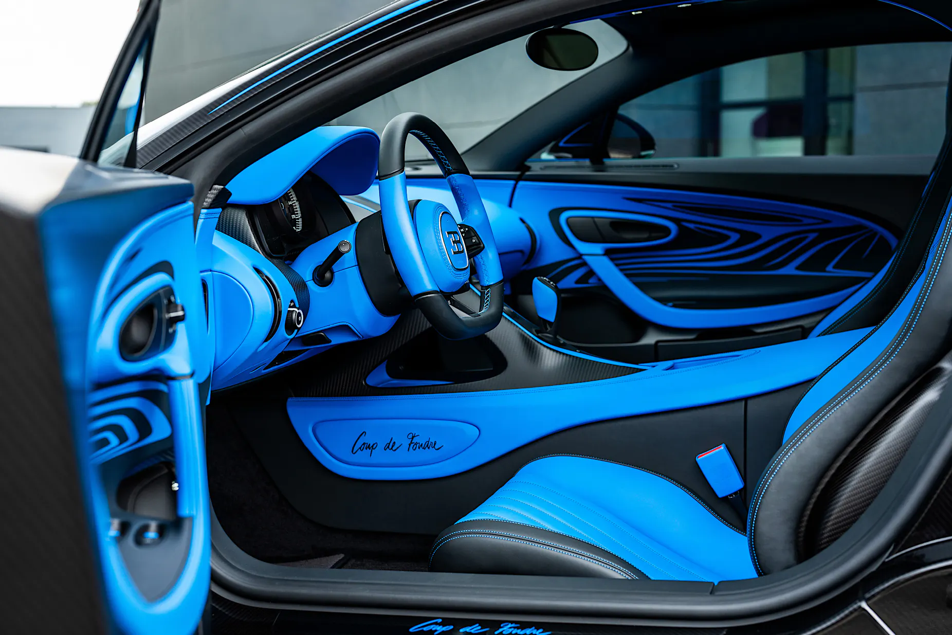 the interior of a black car with blue seats and a steering wheel